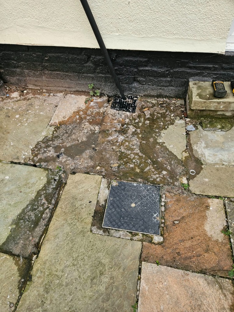 Typical sign of an external drainage blockage overflowing onto patio flags
